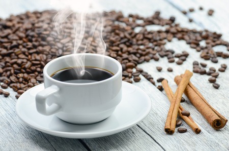 Coffee cup with smoke and coffee beans aroundの写真素材