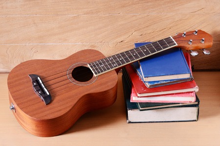ukulele and stack of old book on wooden table