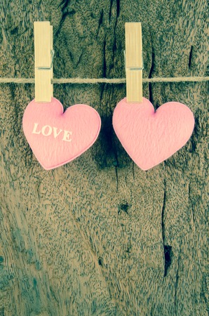 lovely pink hearts hanging on the clothesline on old wood backgroundの写真素材