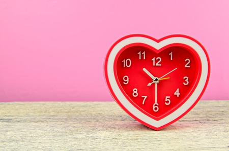 Red heart clock on white wood tableの写真素材