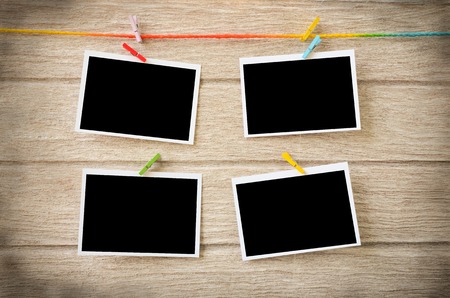 empty black photo frames hanging with clothespins on wooden background
