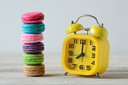 colorful stack of macarons and yellow clockの写真素材