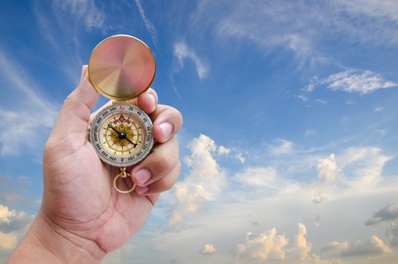 Man hand and compass with blue sky background