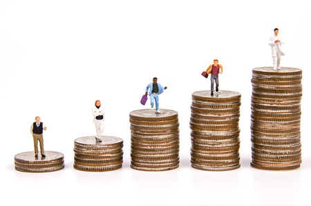 Miniature people on stack of coinsの写真素材