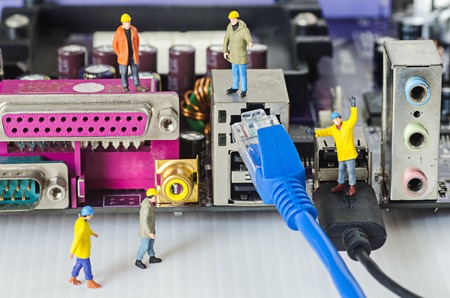 Miniature engineer team try to connect ethernet cables to portの写真素材