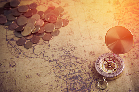 Vintage compass and coins on old mapの写真素材