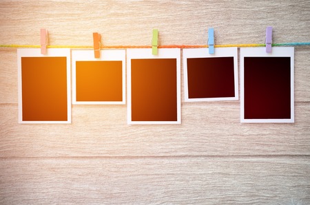 empty black photo frames hanging with clothespins on wooden background in vintage toneの写真素材