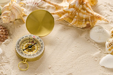 compass and sea shells on sand