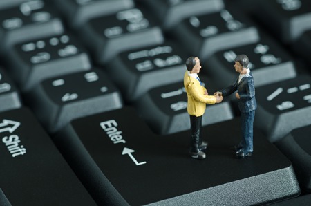 miniature people shake hand on keyboard backgroudの写真素材