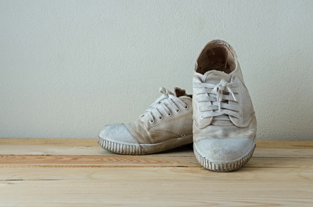 grunge white sport shoes on wooden tableの写真素材