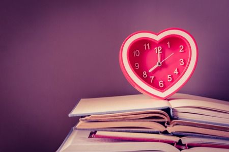 alarm clock on stack of open bookの写真素材