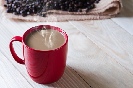 coffee cup with smoke and coffee beans aroundの写真素材
