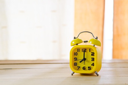 Yellow alarm clock on wood tableの写真素材