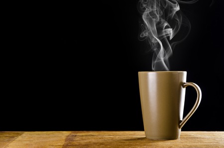 brown coffee cup with smoke on black backgroundの写真素材