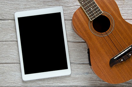 tablet and ukulele guitar on white wooden tableの写真素材
