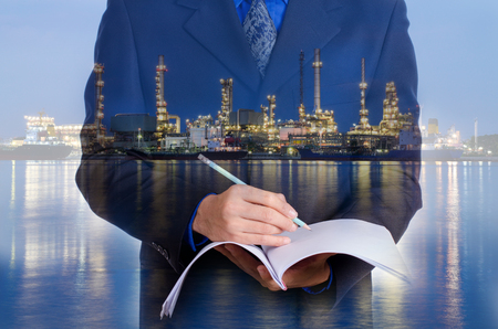 Double exposure of business man and oil refinery backgroundの写真素材