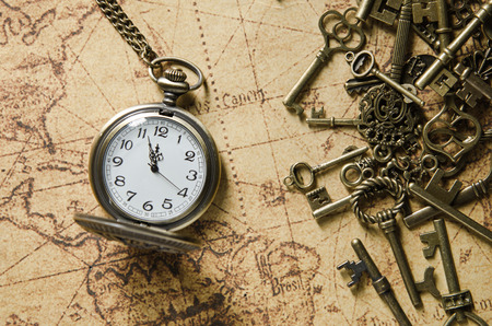 vintage pocket watch and skeleton key on ancient map backgroundの写真素材