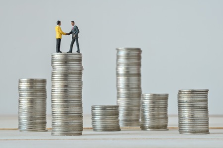 miniature people agreement on stack of coins