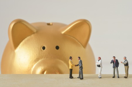 miniature people agreement with gold piggy bank backgroundの写真素材