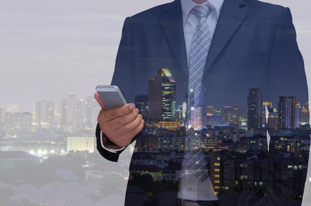 double exposure of business man using telephone and night modern city backgroundの写真素材