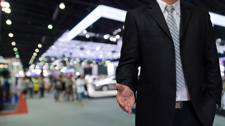business man with welcome hand and blurry event backgroundの写真素材