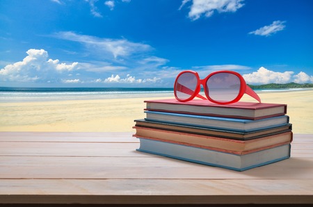 red sun glasses on stack of book with seascape backgroundの写真素材