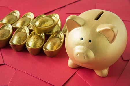 Gold piggy bank and chinese golden ingots on red envelope : Chinese new year themeの写真素材