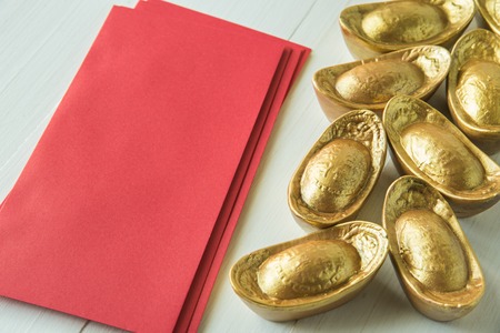 Chinese golden ingots and red envelope on wooden table : Chinese new year themeの写真素材