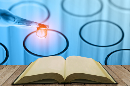 open book on wooden table with science laboratory test tubes background