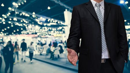 business man with welcome hand in blurry event backgroundの写真素材