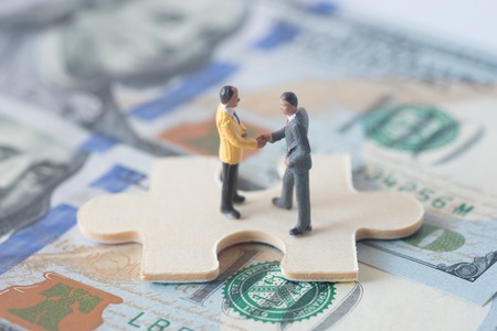 miniature businessman team make agreement on jigsaw puzzleの写真素材