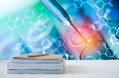 book stack on white table with science laboratory test tubes backgroundの写真素材