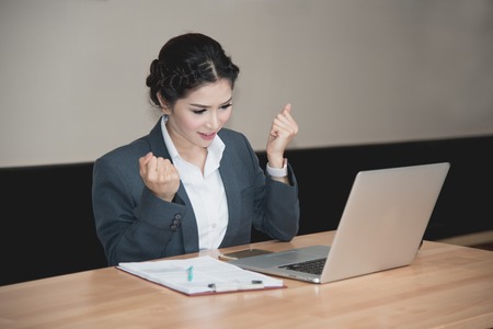 business woman happy when work success with laptop on wooden tableの写真素材