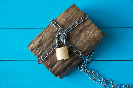 locked wooden treasure box on blue wood backgroundの写真素材