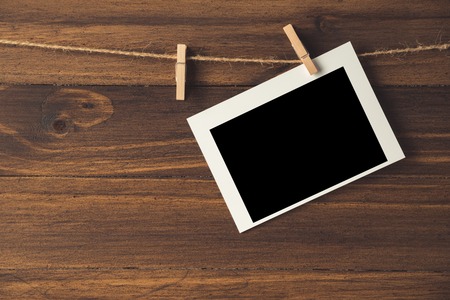 empty photo frames hanging with clothespins on wooden background
