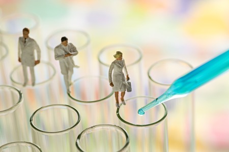 Miniature scientist checking chemical in laboratory test tubeの写真素材