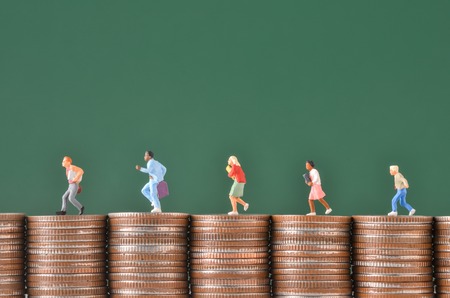 miniature people worker run on stack of coinsの写真素材