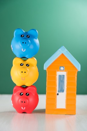 piggy bank and house model on green backgroundの写真素材