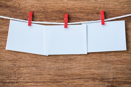 empty three white photo frames hanging with clothespins on wooden background