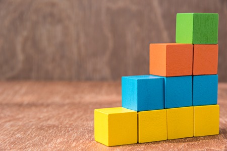 stack of colorful wood cube building blocks on wood background