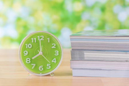 green clock and stack of book on wooden tableの写真素材