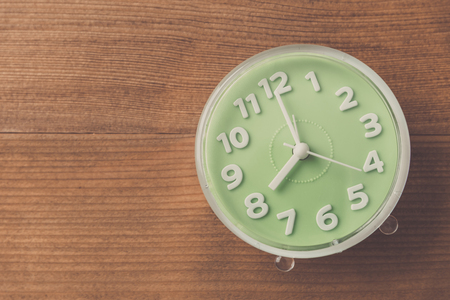 alarm clock on wood table , vintage tone