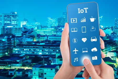 woman hand using smart phone in concept internet of things with night modern city background