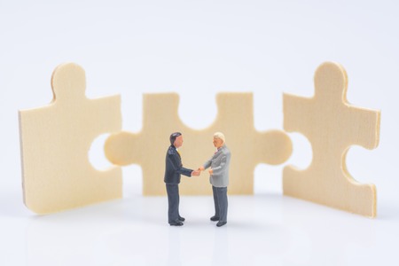 business miniature people shaking hands on jigsaw puzzle pieces backgroundの写真素材
