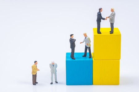 business miniature people shaking hands on stack of wood cube building blackの写真素材