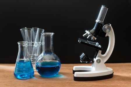 science laboratory test tubes and white microscope on wooden table with black background , laboratory equipmentの写真素材