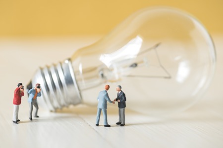 business miniature people make handshaking agreement with light bulb backgroundの写真素材
