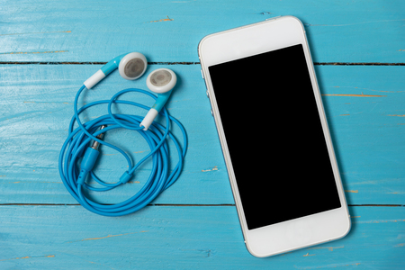 mobile phone and blue earphone on blue wood backgroundの写真素材
