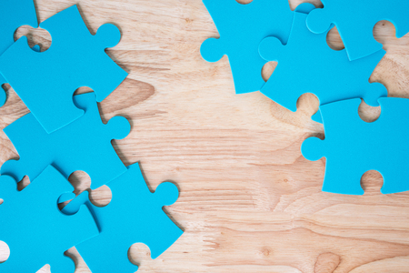 blue jigsaw puzzle pieces on wooden backgroundの写真素材