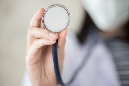 confidential woman doctor with green stethoscope in handの写真素材